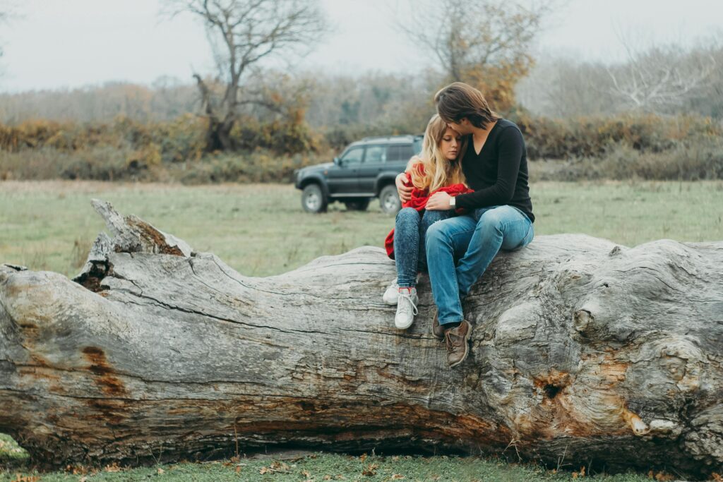 pexels-photo-840566-840566 A couple embraces tenderly on a large fallen tree, set against a serene natural landscape.
